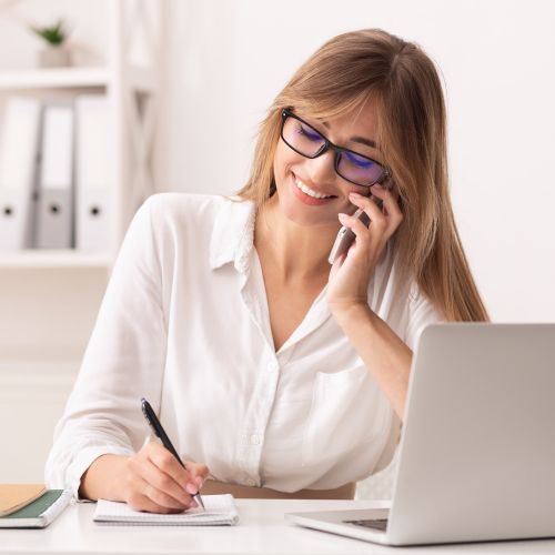 cheerful-businesswoman-talking-on-cellphone-sittin-NPKVJUW-min (1)